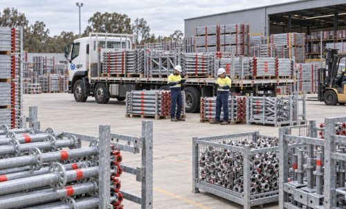 APS yard with a truck loaded with stillaged Layher scaffold, staff in hi-vis and galvanised components ready for hire