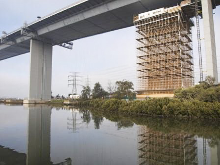 Scaffold tower built around a concrete bridge pier over a river