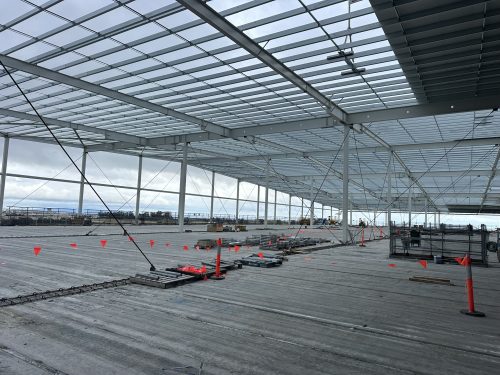 Steel roof framing and purlins over a concrete slab at a large industrial construction site